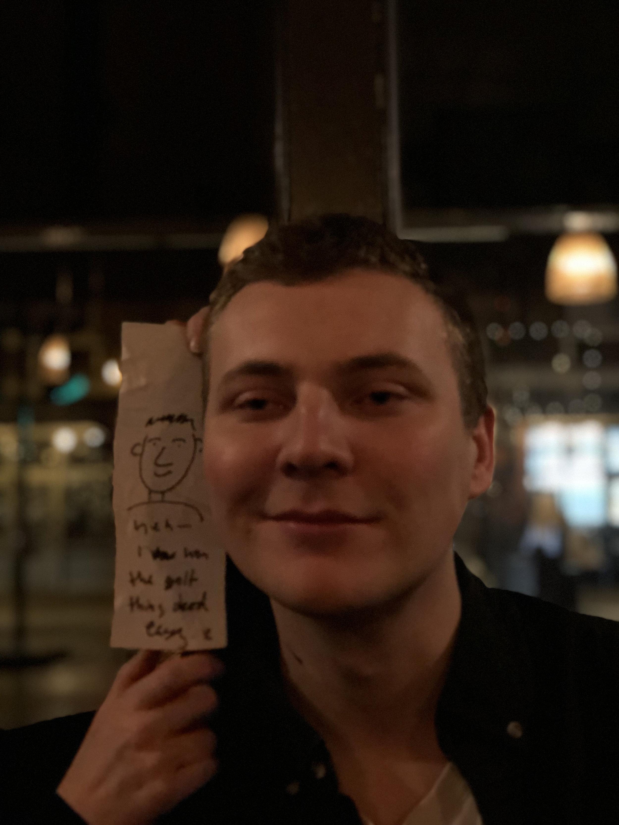Reece smiling holding up Sams receipt drawing of him