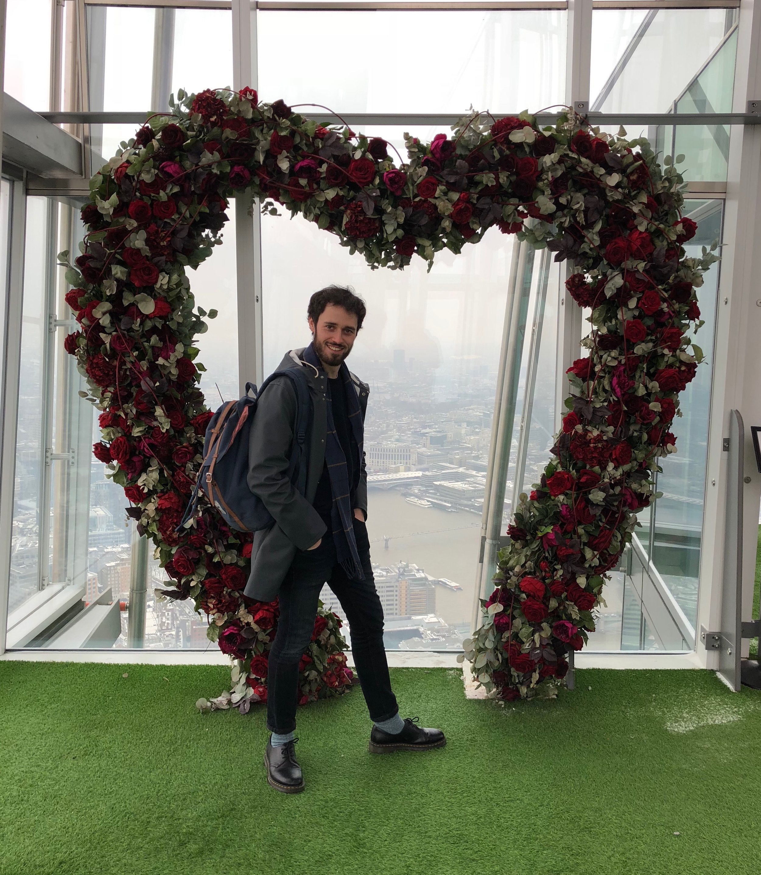 A smiling Tim stood inside a heart shaped rose arch